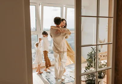 Happy family with two children dancing in a sunlit living room representing family therapy and healthy dynamics.