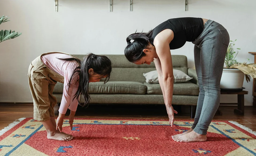 Mother and child practicing yoga stretch together at home