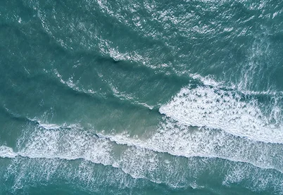 Aerial view of turquoise ocean waves ebbing and flowing onto a sandy beach, representing rhythm and fluidity in sexual wellness.