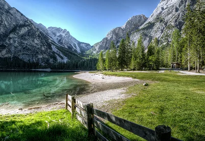 Clear alpine lake and mountain landscape behind a wooden fence, symbolizing clarity and healthy boundaries in substance use recovery.