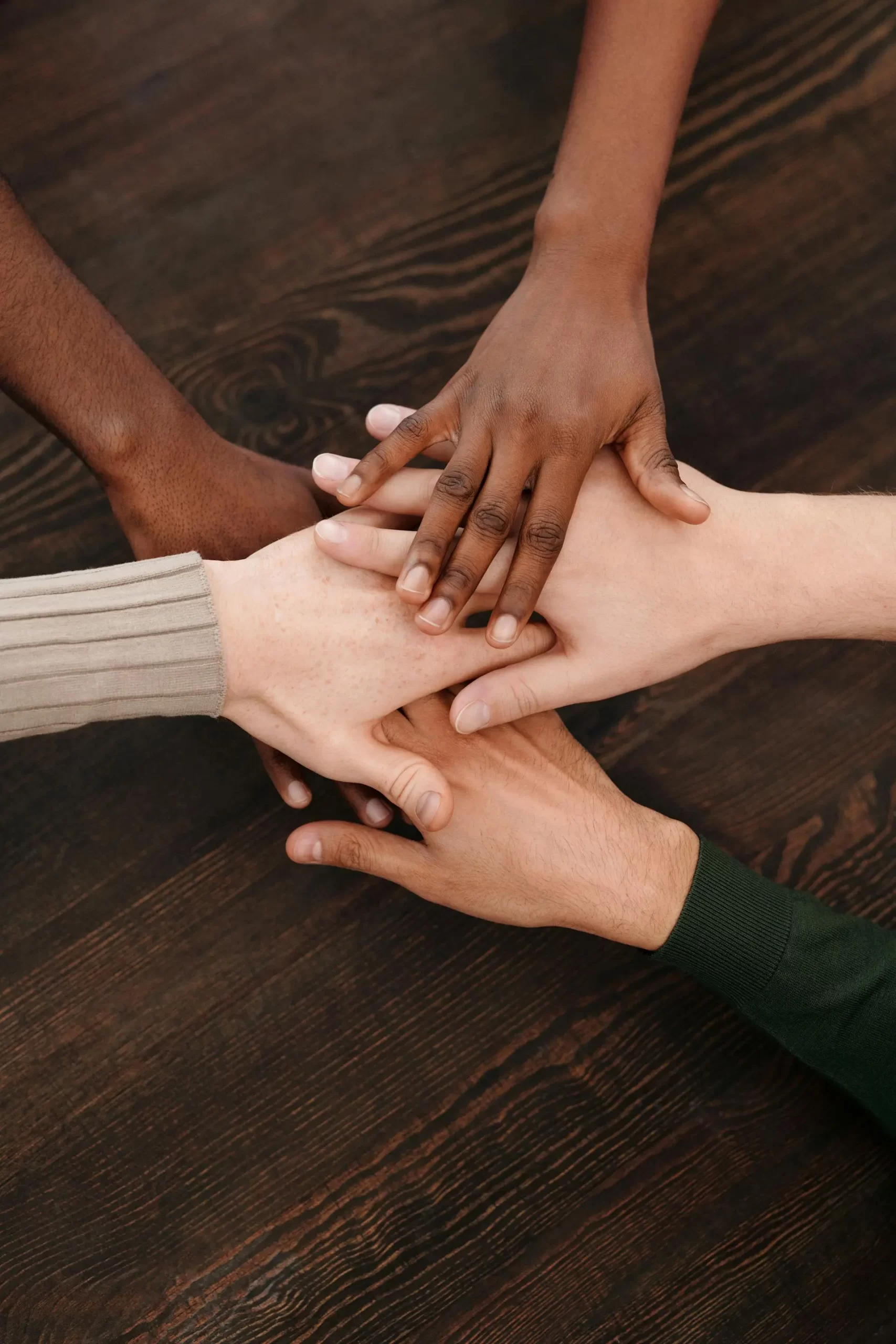Diverse group of hands from different cultural backgrounds reaching together in unity