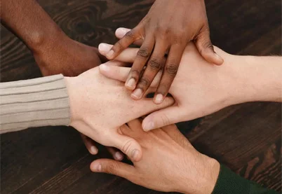 Diverse group of hands from different cultural backgrounds reaching together in unity